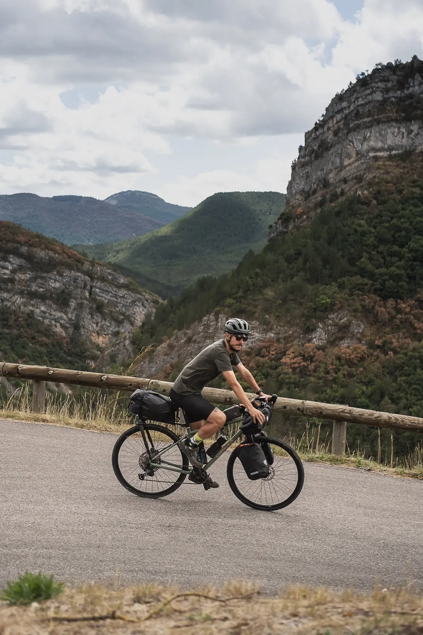 Un cyclotouriste et son vélo chargé de sacoches sur une route de montagne